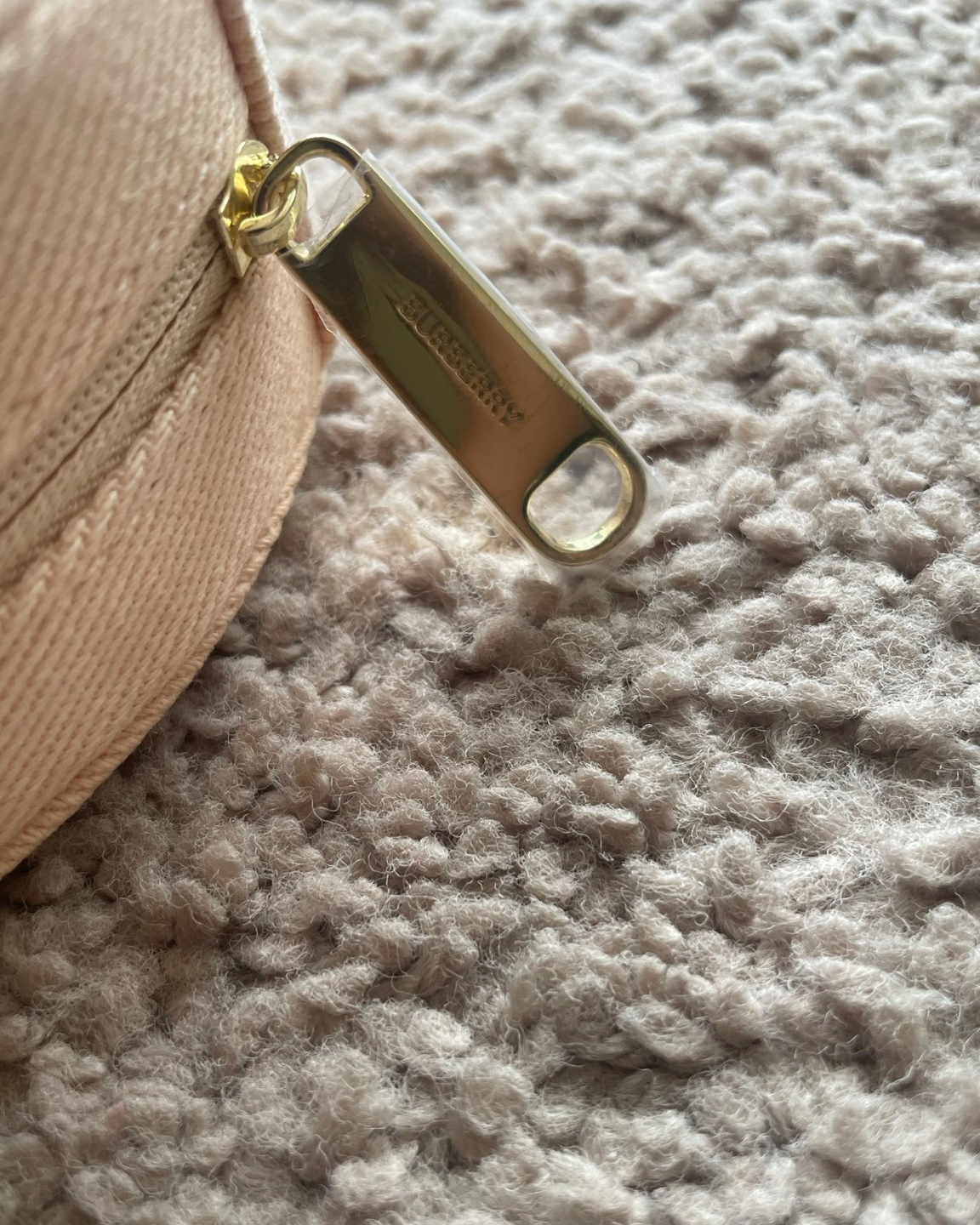 Close-up of a beige cap with a gold zipper on a textured surface