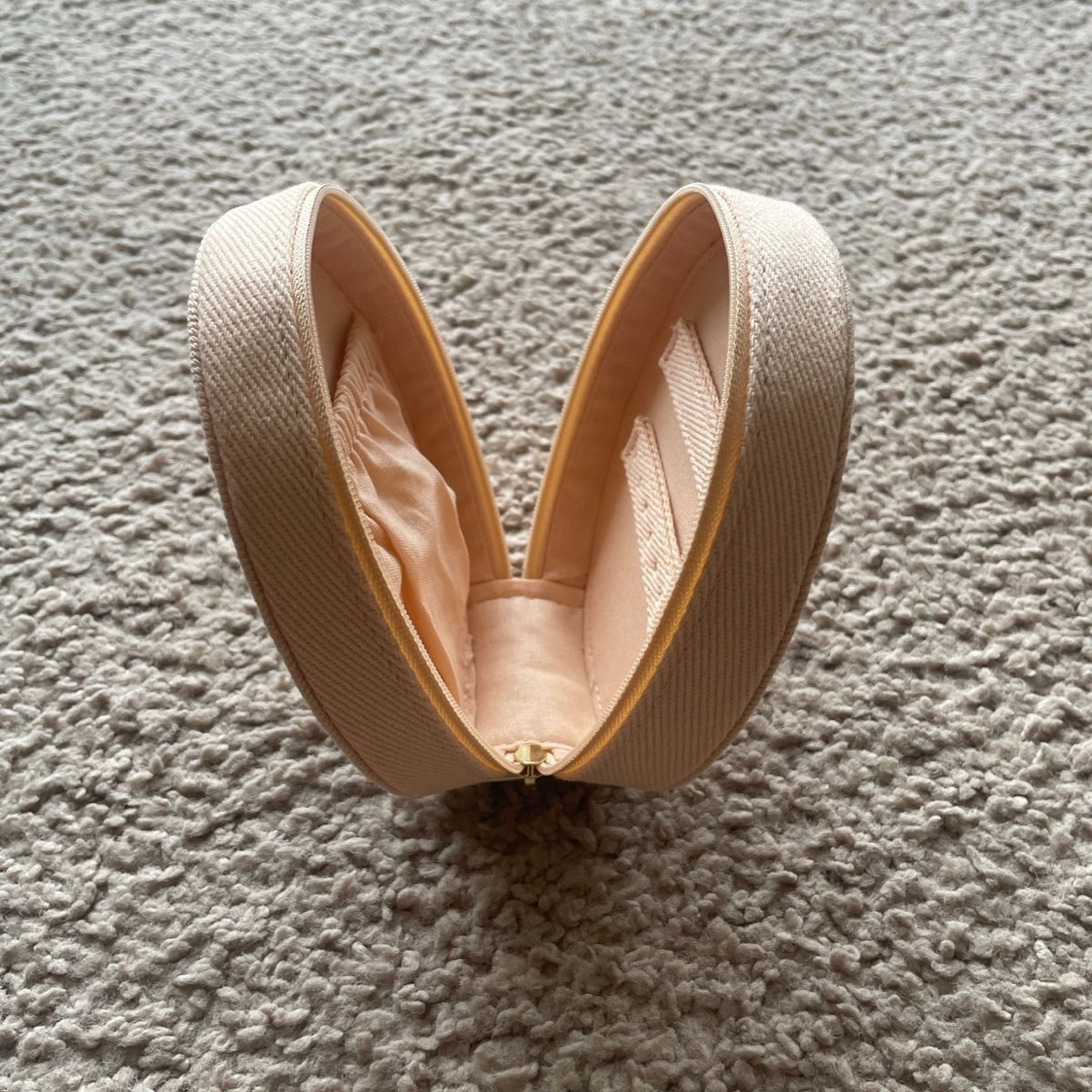 Beige makeup case on a textured cream colored surface