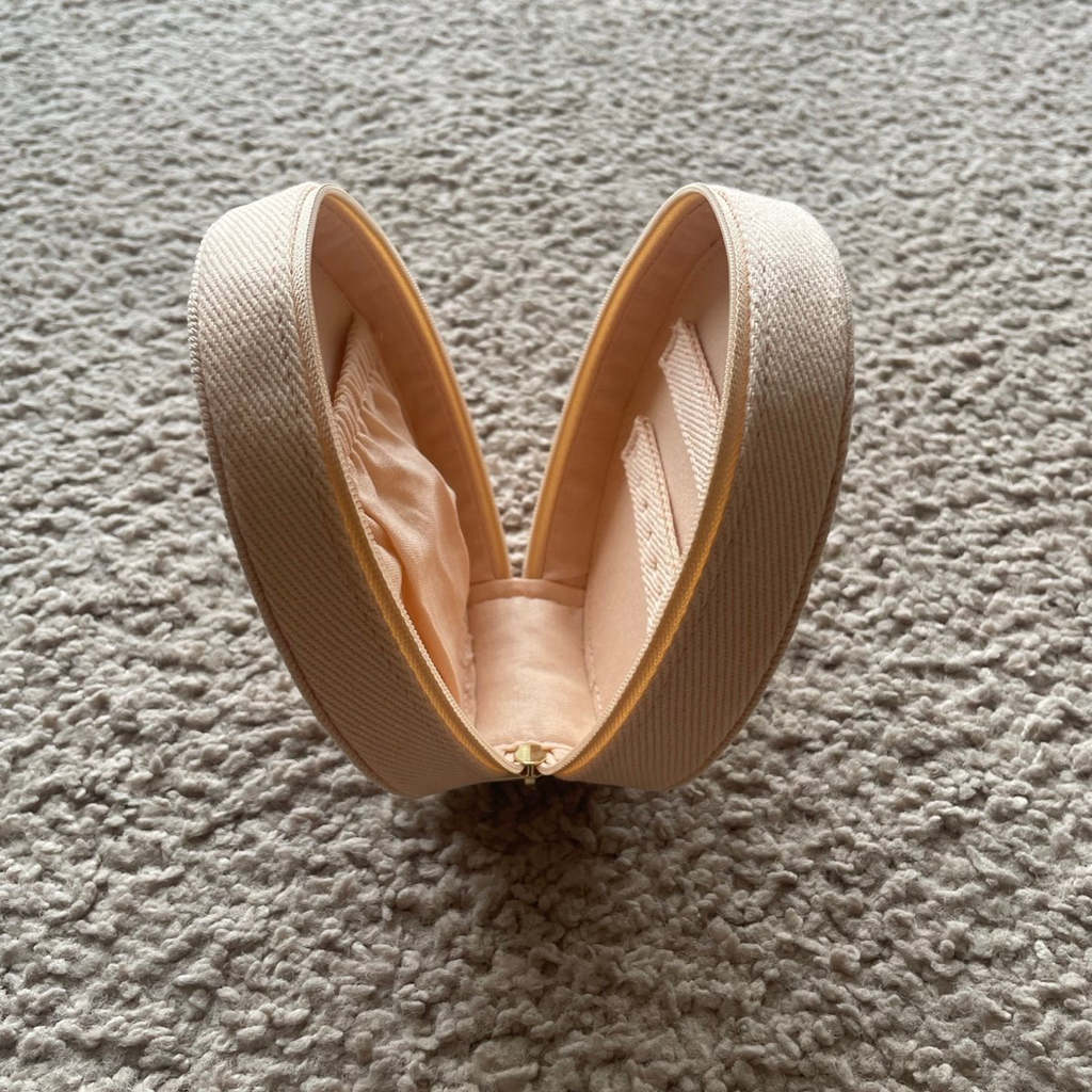 Beige makeup case on a textured cream colored surface
