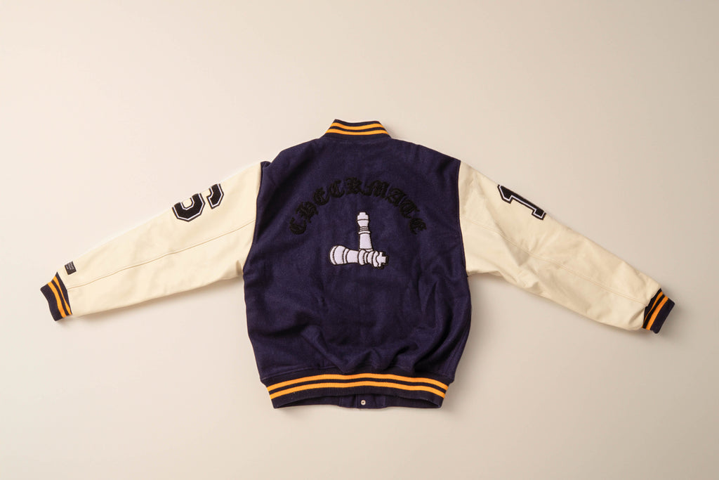 Checkmate anywear navy and yellow varsity jacket with embroidered design on neutral background