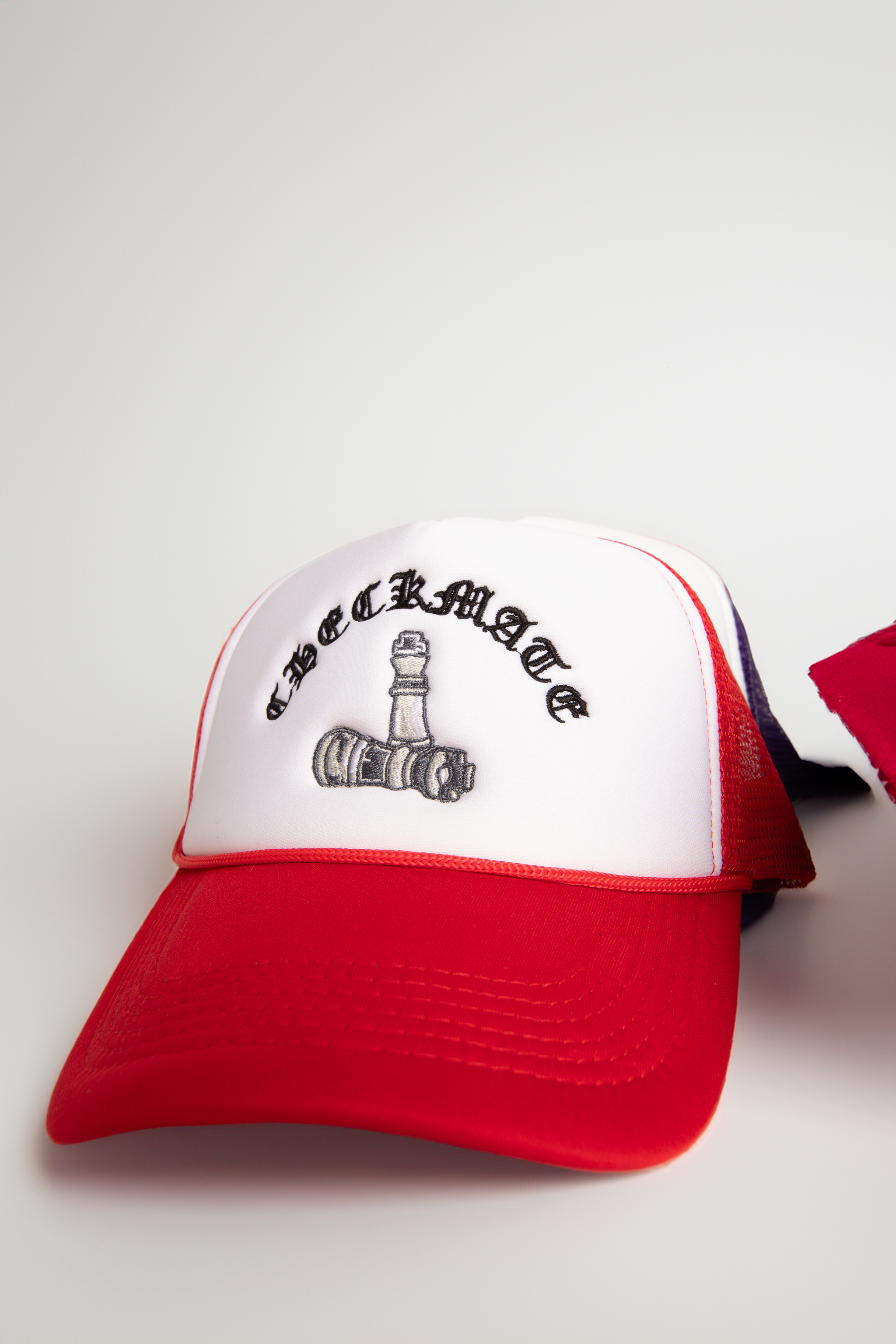 Red and white cap with black text and logo on a neutral background